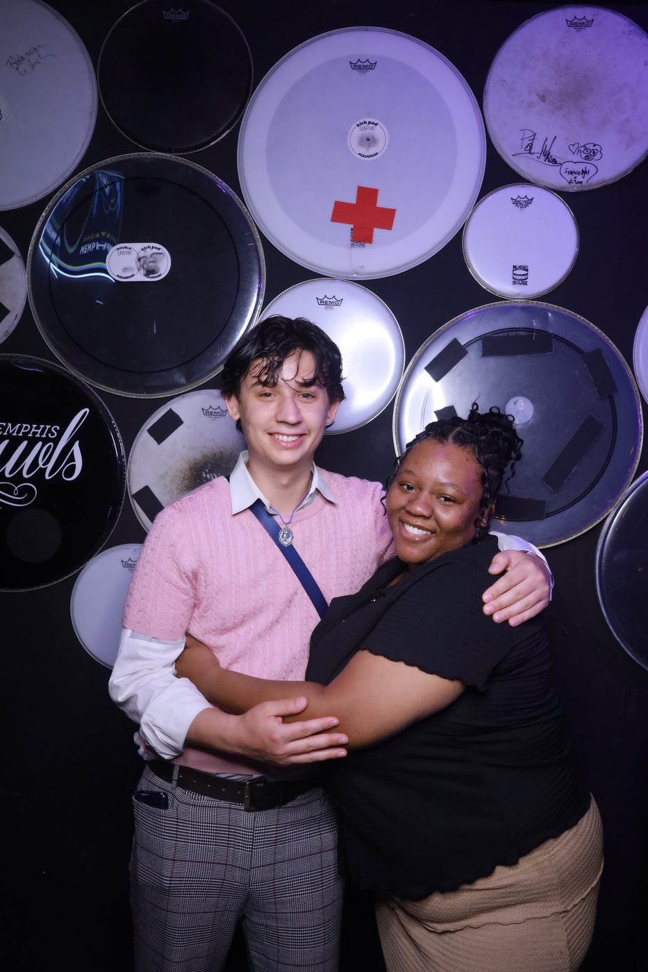 Two guests hugging at a photo booth with a drum-head backdrop